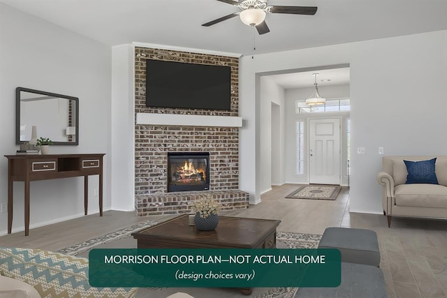 living room with a brick fireplace, wood-type flooring, and ceiling fan