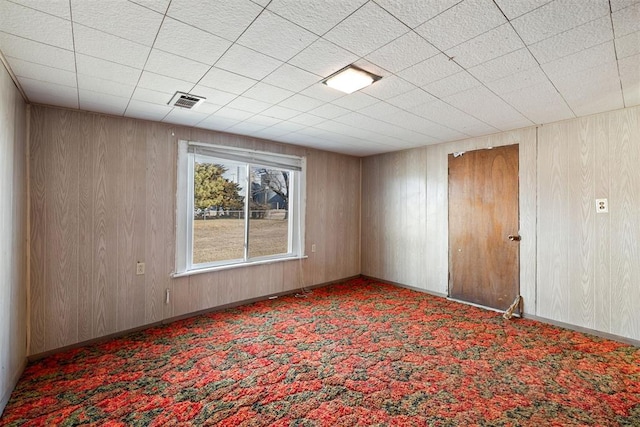 carpeted spare room with wooden walls