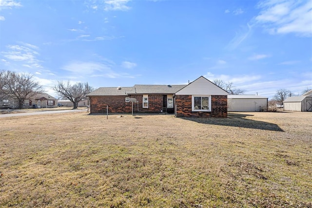 rear view of house with a yard and a storage unit