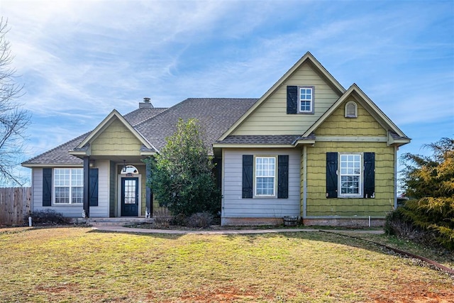 view of front of home featuring roof with shingles, a chimney, fence, and a front yard