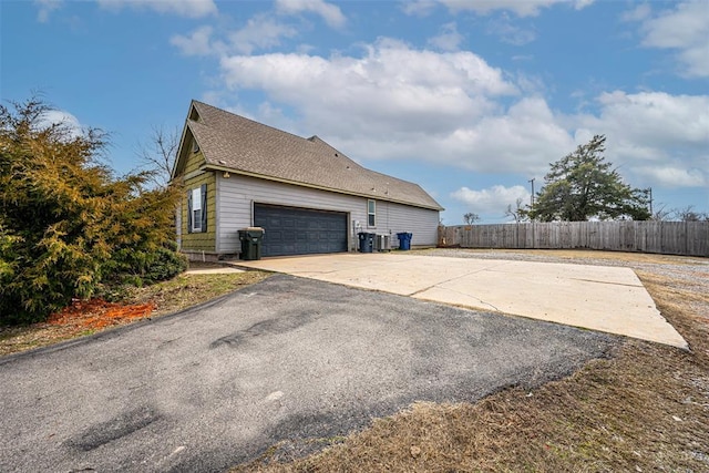 view of home's exterior with central AC, roof with shingles, fence, and driveway