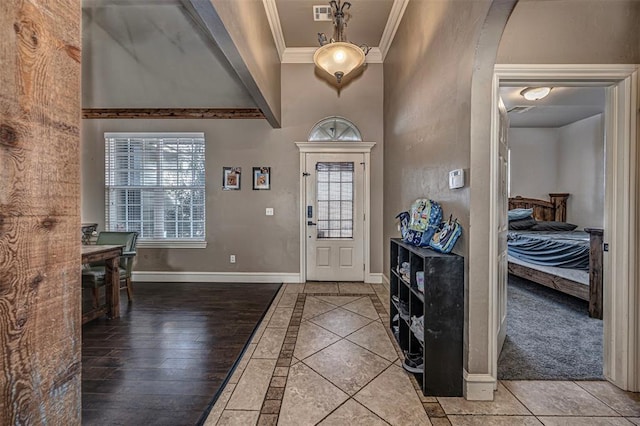 entryway with arched walkways, visible vents, ornamental molding, tile patterned flooring, and baseboards