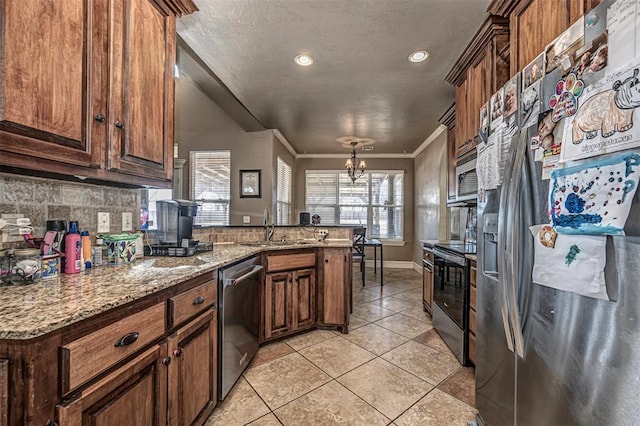 kitchen with light tile patterned floors, appliances with stainless steel finishes, ornamental molding, a sink, and a peninsula