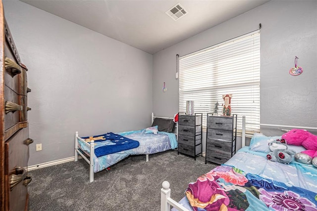 bedroom with baseboards, visible vents, dark colored carpet, and a textured wall