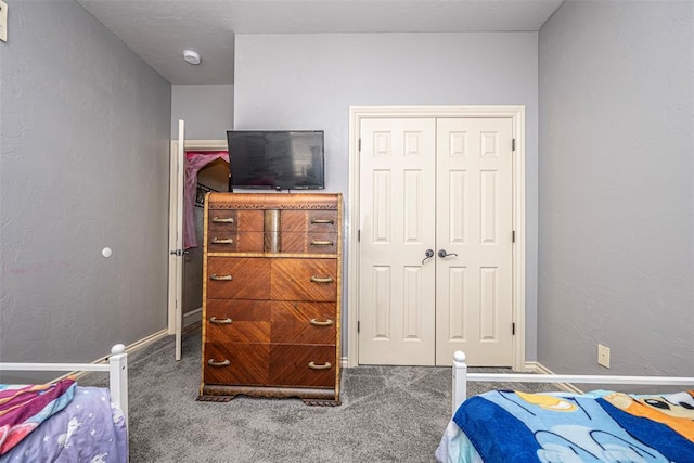 carpeted bedroom featuring a textured wall, a closet, and baseboards