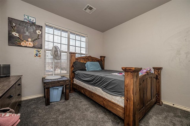 bedroom with a textured wall, visible vents, dark carpet, and baseboards