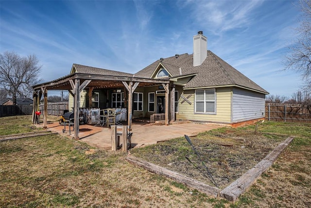 rear view of property with a patio, a fenced backyard, a shingled roof, a yard, and a chimney