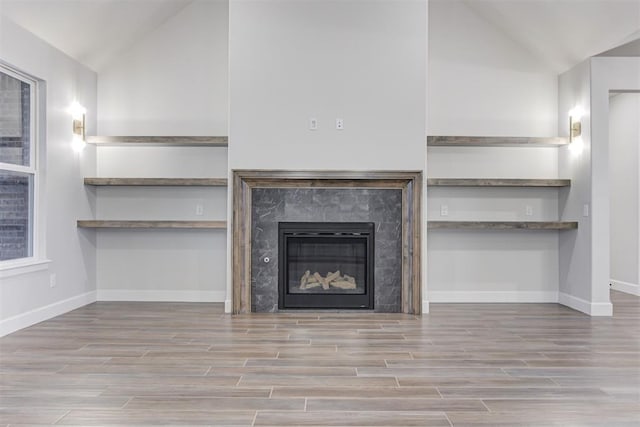 unfurnished living room featuring vaulted ceiling and a high end fireplace