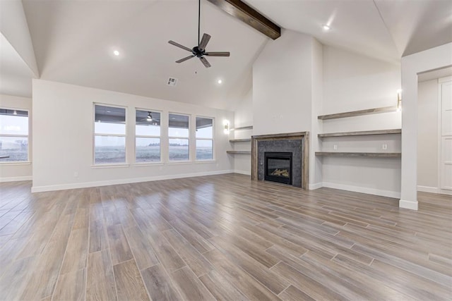 unfurnished living room featuring high vaulted ceiling, beam ceiling, light hardwood / wood-style floors, and ceiling fan