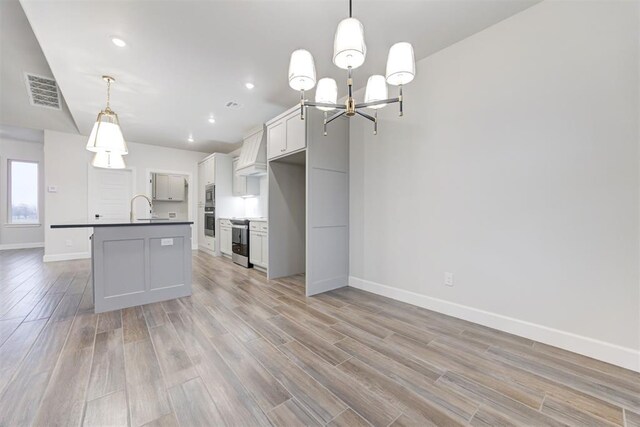 kitchen featuring pendant lighting, sink, appliances with stainless steel finishes, a kitchen island with sink, and custom exhaust hood