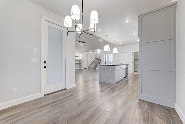 kitchen featuring pendant lighting, sink, a center island with sink, and light wood-type flooring