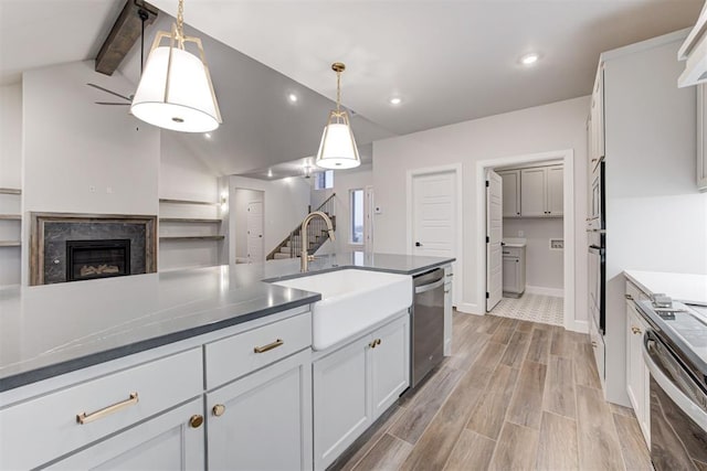 kitchen featuring pendant lighting, sink, white cabinetry, lofted ceiling with beams, and stainless steel dishwasher