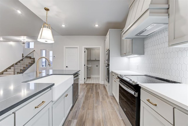 kitchen with pendant lighting, sink, appliances with stainless steel finishes, white cabinets, and custom exhaust hood