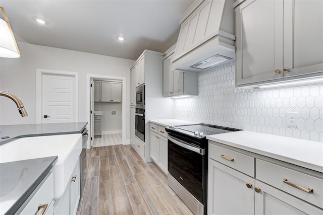 kitchen featuring stainless steel appliances, premium range hood, and decorative backsplash