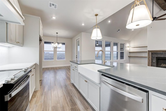 kitchen featuring sink, appliances with stainless steel finishes, light hardwood / wood-style floors, white cabinets, and decorative light fixtures