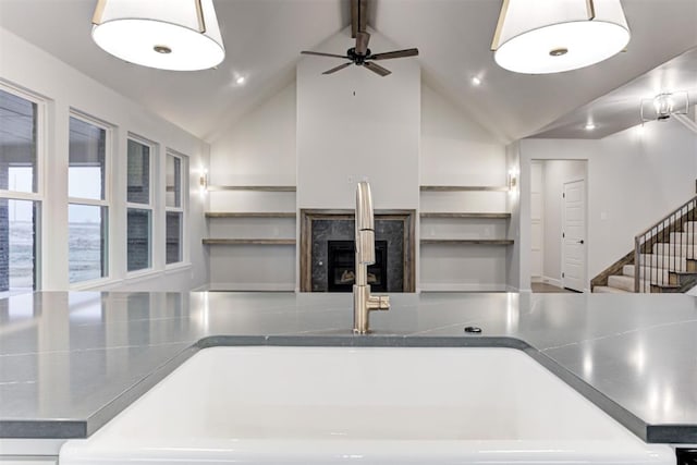 kitchen featuring sink, beam ceiling, hanging light fixtures, ceiling fan, and a fireplace