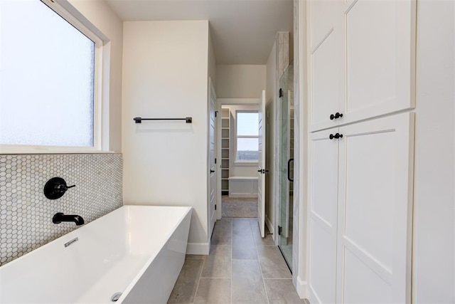 bathroom featuring tasteful backsplash, a bath, and tile patterned floors