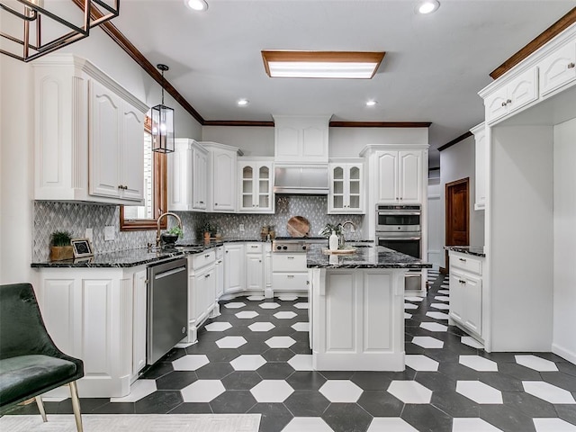 kitchen with decorative light fixtures, a center island, dark stone countertops, stainless steel appliances, and white cabinets