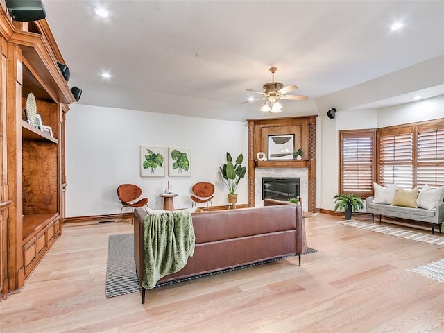 living room with ceiling fan, a fireplace, and light hardwood / wood-style floors