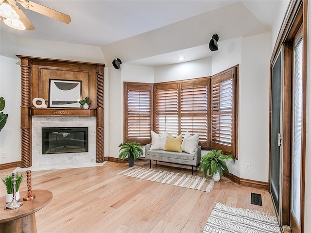 sitting room featuring ceiling fan, a fireplace, and light hardwood / wood-style floors