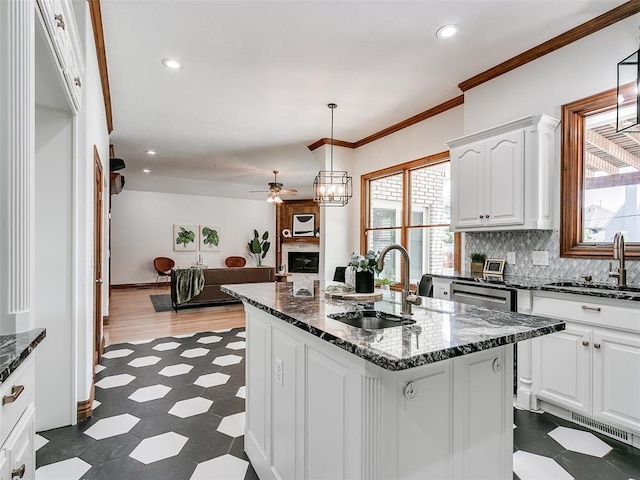 kitchen with pendant lighting, sink, white cabinetry, and a kitchen island with sink