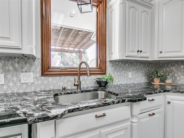 kitchen with tasteful backsplash, dark stone counters, sink, and white cabinets