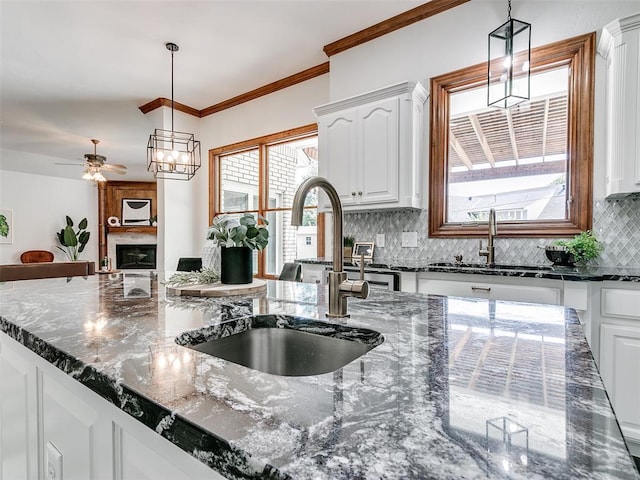 kitchen featuring dark stone countertops, sink, pendant lighting, and white cabinets