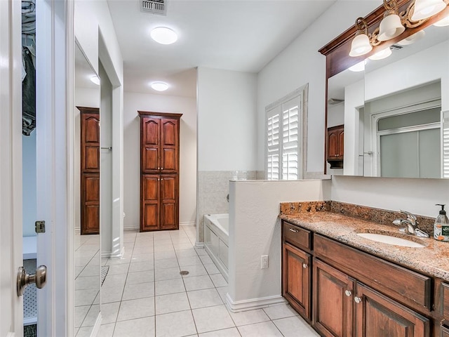 bathroom with tile patterned floors, tiled bath, and vanity