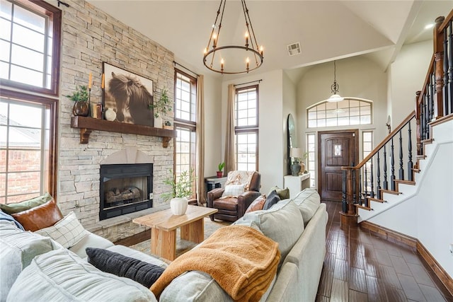 living room with a high ceiling, a stone fireplace, plenty of natural light, and dark hardwood / wood-style flooring