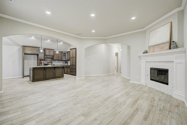 living room featuring ornamental molding, sink, light hardwood / wood-style floors, and a tile fireplace