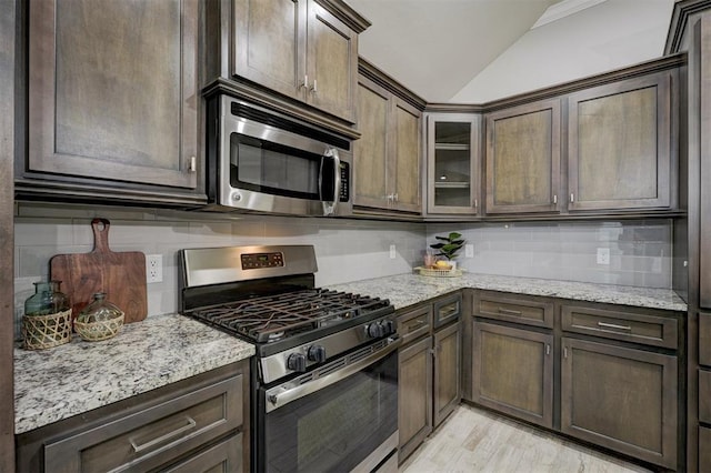 kitchen with tasteful backsplash, appliances with stainless steel finishes, vaulted ceiling, and dark brown cabinets