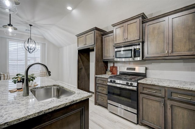 kitchen featuring sink, hanging light fixtures, dark brown cabinets, stainless steel appliances, and light stone counters