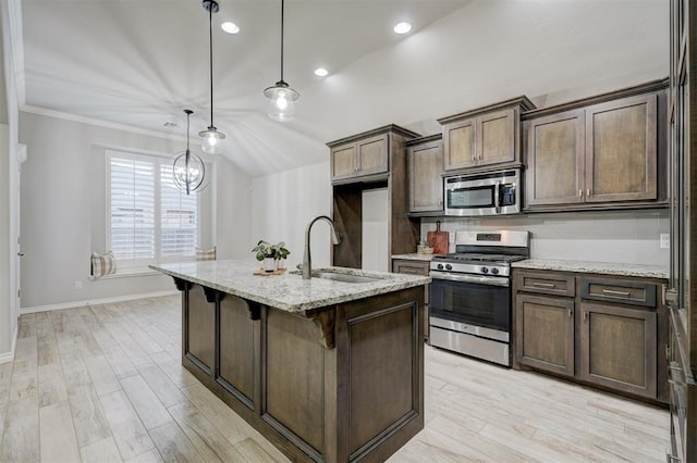 kitchen with pendant lighting, sink, light stone countertops, and appliances with stainless steel finishes