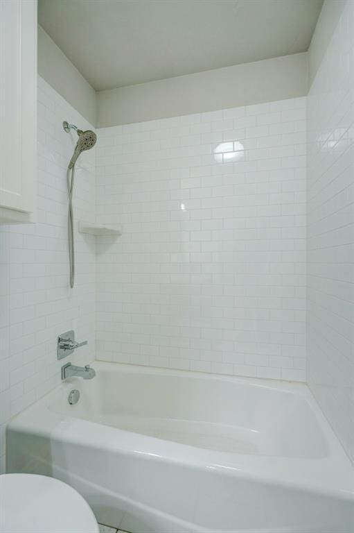 bathroom featuring toilet and tiled shower / bath combo