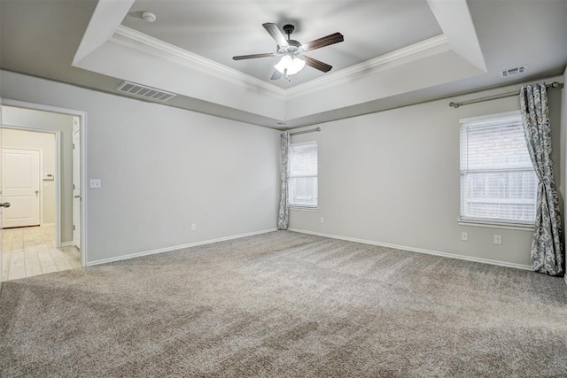 carpeted empty room with ceiling fan, ornamental molding, and a raised ceiling