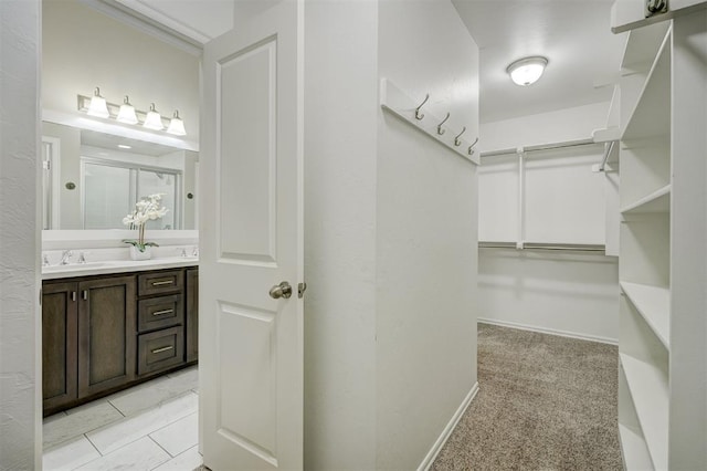 walk in closet featuring light colored carpet and sink