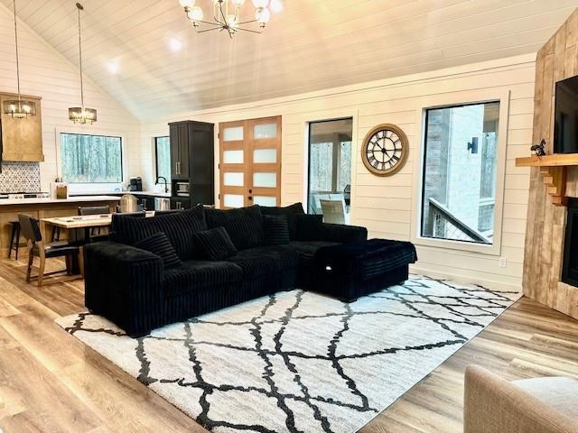 living room featuring an inviting chandelier, wood ceiling, a healthy amount of sunlight, and light wood-type flooring