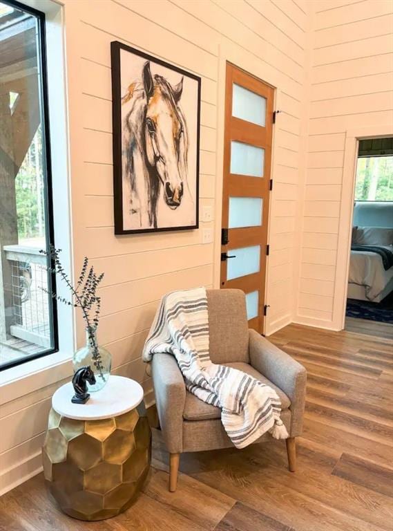 sitting room featuring hardwood / wood-style flooring and wooden walls