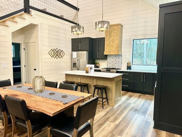 kitchen with pendant lighting, a breakfast bar area, stainless steel fridge, a center island, and light hardwood / wood-style floors