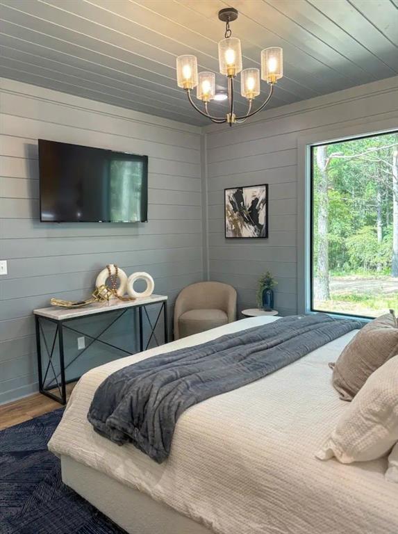 bedroom featuring hardwood / wood-style flooring, wooden ceiling, and an inviting chandelier