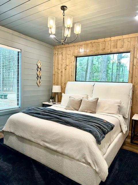 bedroom featuring an inviting chandelier, wooden walls, hardwood / wood-style flooring, and wooden ceiling