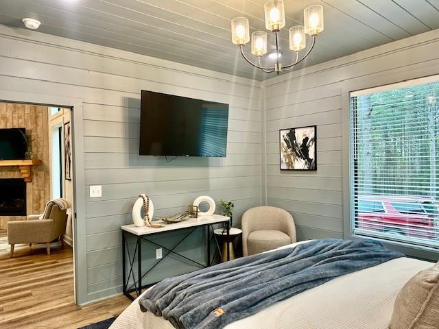 bedroom with hardwood / wood-style flooring, a fireplace, an inviting chandelier, and wood ceiling