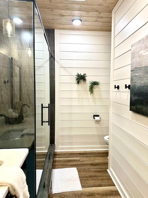 bathroom featuring walk in shower, toilet, wood walls, wood ceiling, and hardwood / wood-style flooring