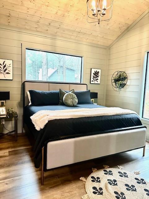 bedroom featuring hardwood / wood-style flooring, vaulted ceiling, wooden ceiling, and a chandelier