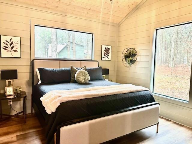 bedroom featuring lofted ceiling, hardwood / wood-style floors, and multiple windows