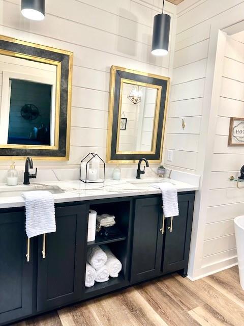 bathroom featuring wood walls, vanity, wood-type flooring, and a tub