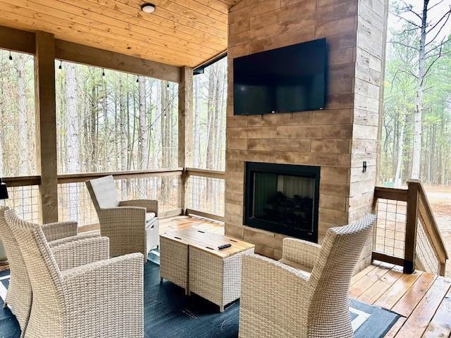 sunroom featuring a large fireplace and wooden ceiling