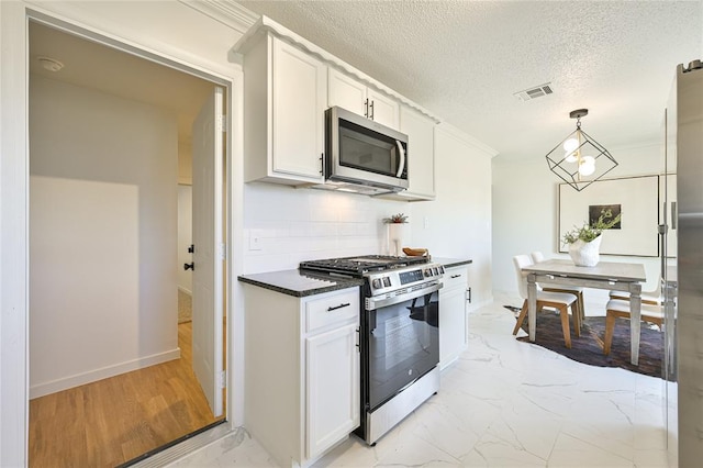 kitchen with white cabinetry, backsplash, decorative light fixtures, and stainless steel appliances