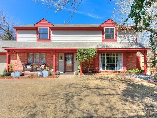 view of front of property featuring a garage, brick siding, and covered porch