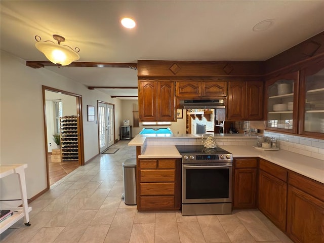 kitchen featuring stainless steel electric range, exhaust hood, kitchen peninsula, and a healthy amount of sunlight